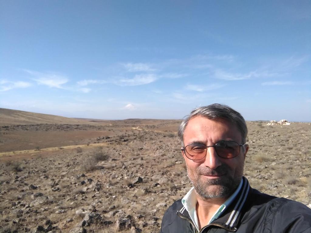 a man wearing glasses standing in a rocky field at Art home 2 in Vagharshapat