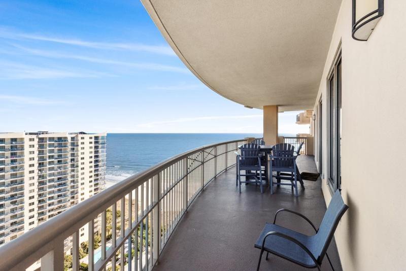 a balcony with chairs and a table and the ocean at Luxurious beautifully decorated ocean view condo in beachfront building in Myrtle Beach