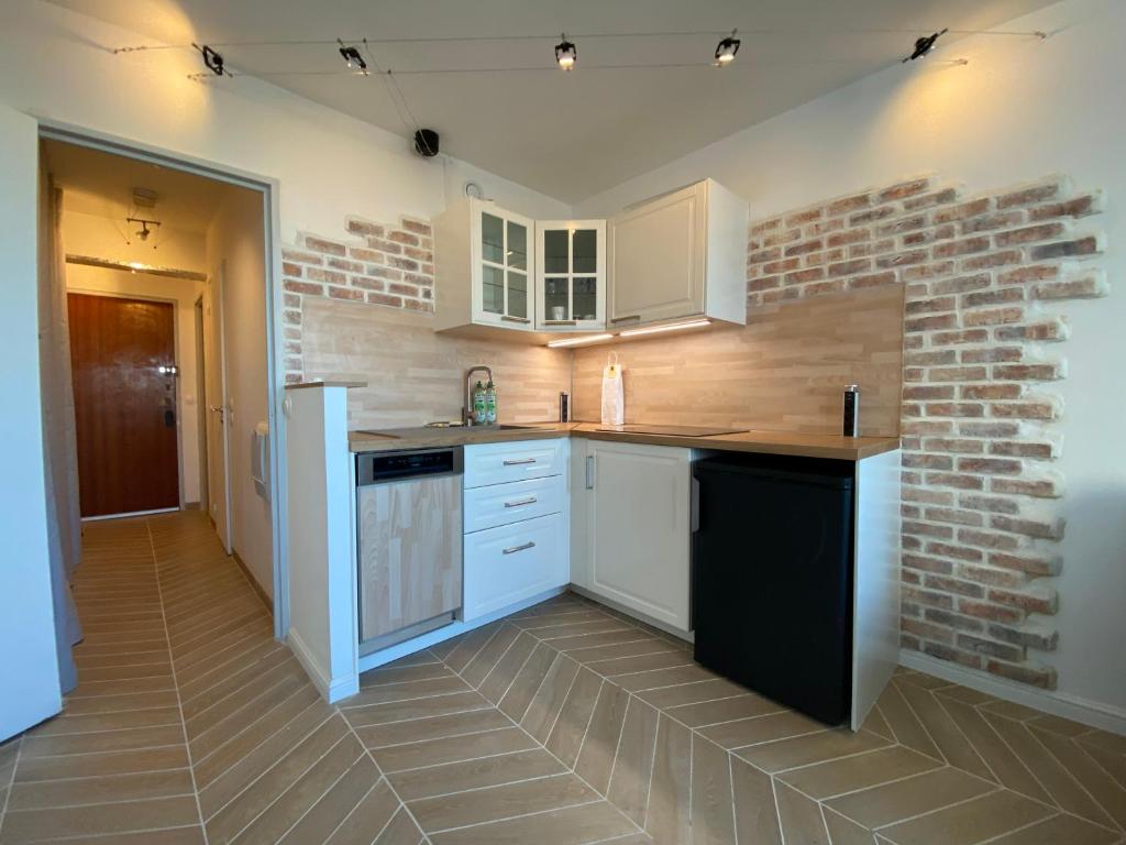 une cuisine avec des placards blancs et un mur en briques dans l'établissement Full Loft in PARIS - 2 single beds for 2 - Chinatown, à Paris