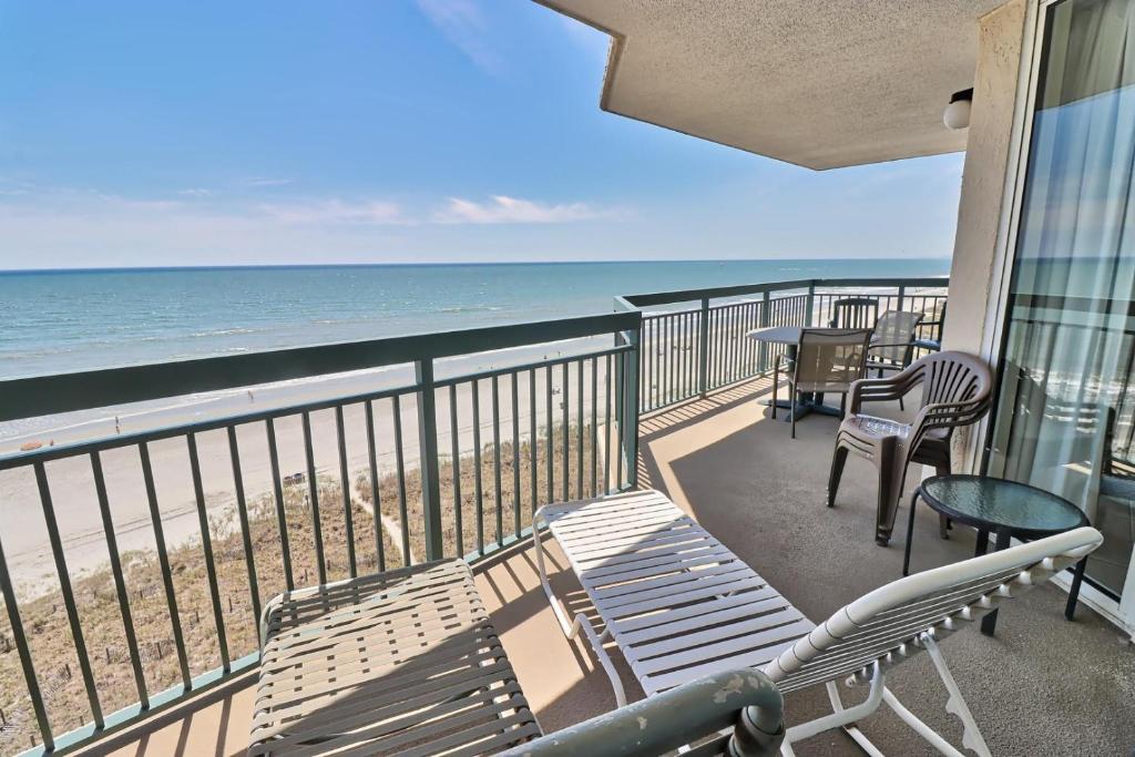 a balcony with chairs and tables and the ocean at Luxurious, Oceanfront condo, spectacular views, beachfront, Wifi, Pools, Monthly in Myrtle Beach