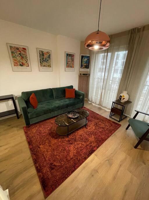 a living room with a green couch and a red rug at Appart charmant au cœur de la ville et des commodités in Saint-Ouen