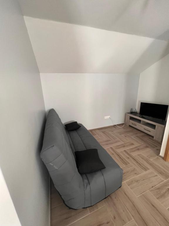 a living room with a grey couch and a television at Gîte chez Audrey et Pascal in Westhouse