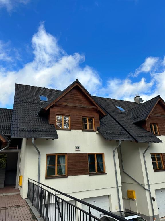 a house with a black roof at Śnieżkowe Love - dwupoziomowy apartament z garażem in Karpacz