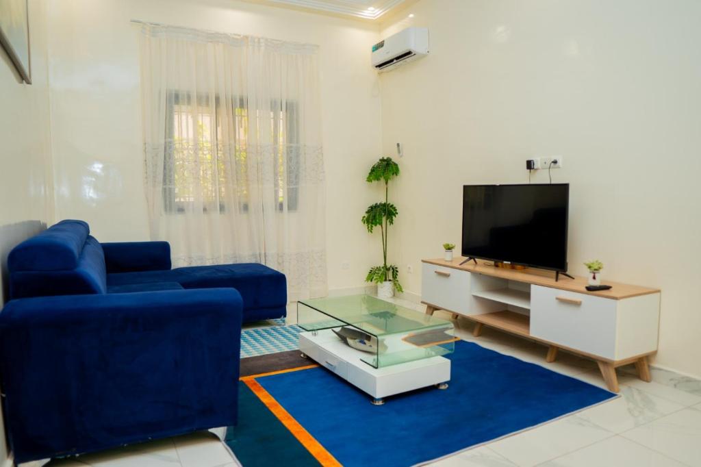 uma sala de estar com um sofá azul e uma televisão em Appartement T2 proche du monument de la Renaissance Africaine em Dakar