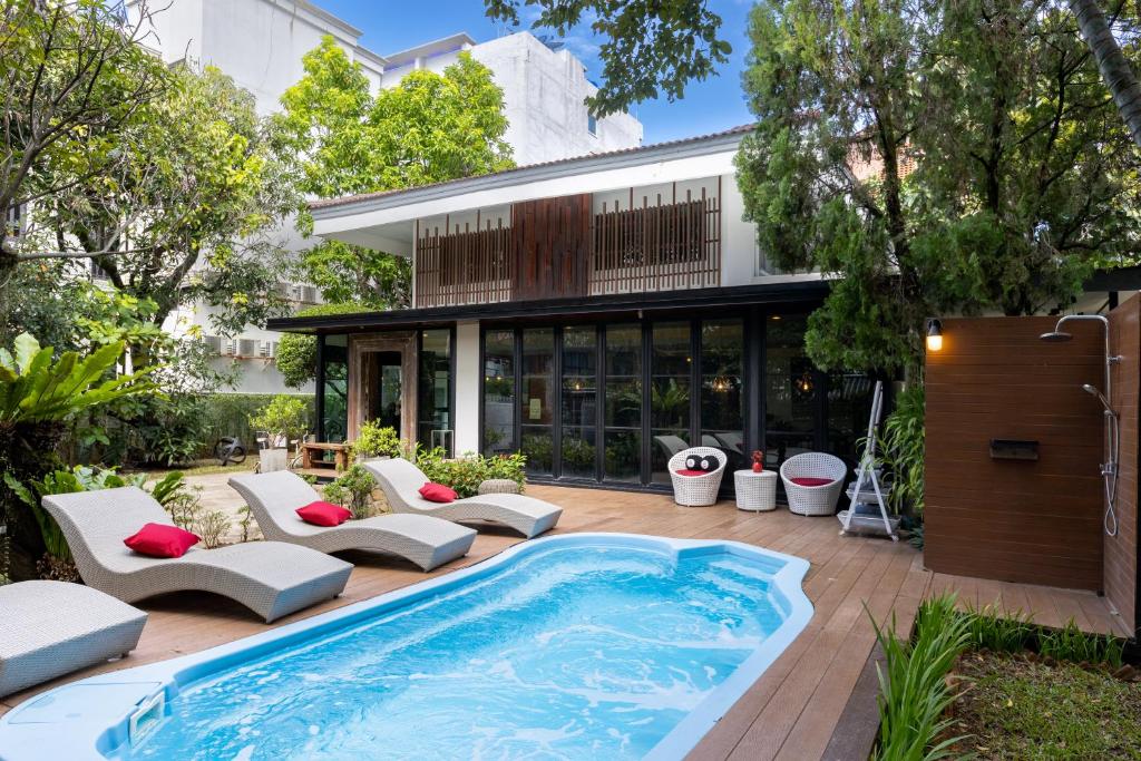 a swimming pool in front of a building with a house at Private Pool Villa 88 Nimman Chiangmai in Chiang Mai