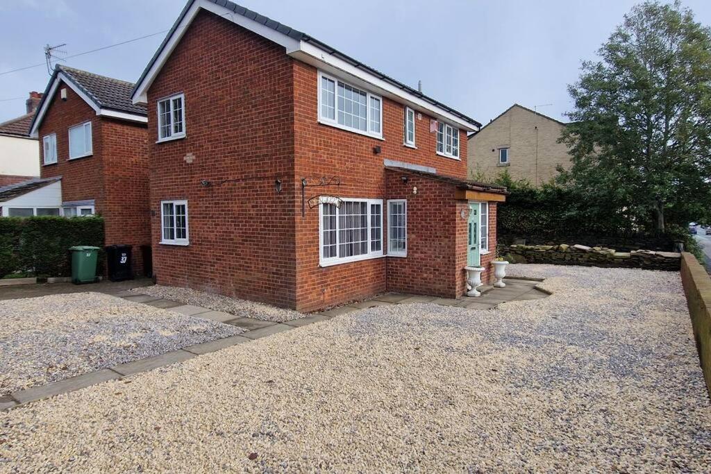 a brick house with white windows and a driveway at Luxury 3 Bed Detached House in Farsley