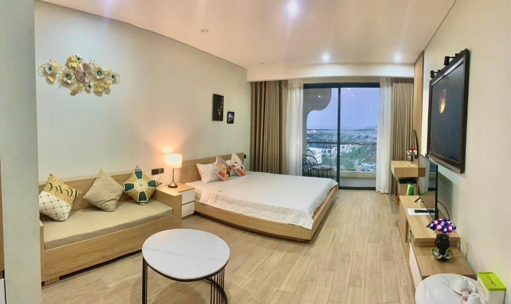 a bedroom with a bed and a couch and a tv at Diva B906 - Homestay CITADINES MARINA HA LONG in Ha Long
