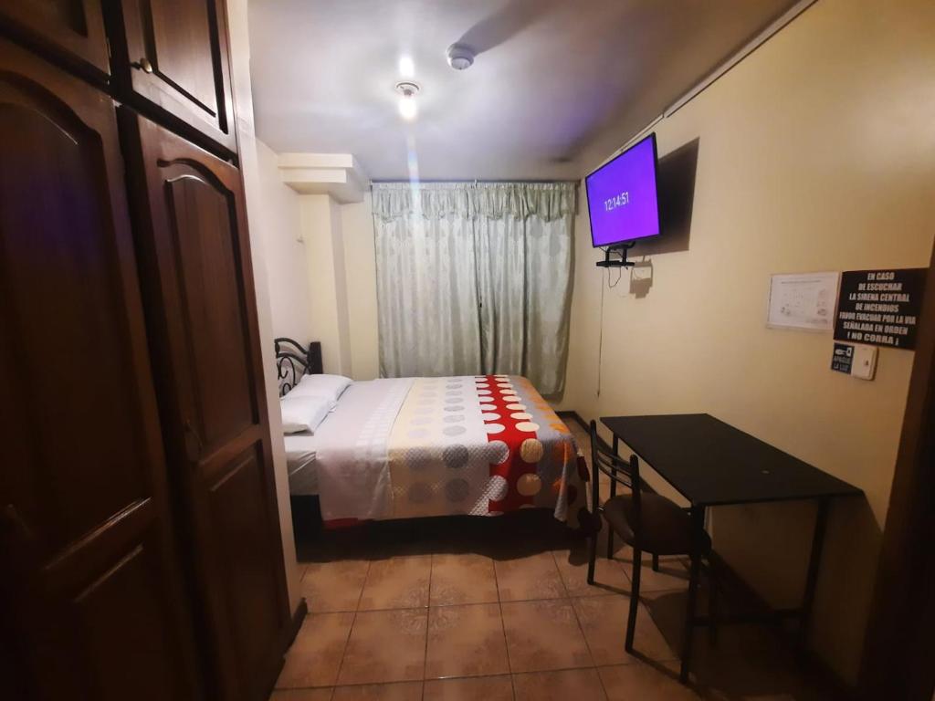 Habitación pequeña con cama y TV. en Hostal David Alejandro, en Quito