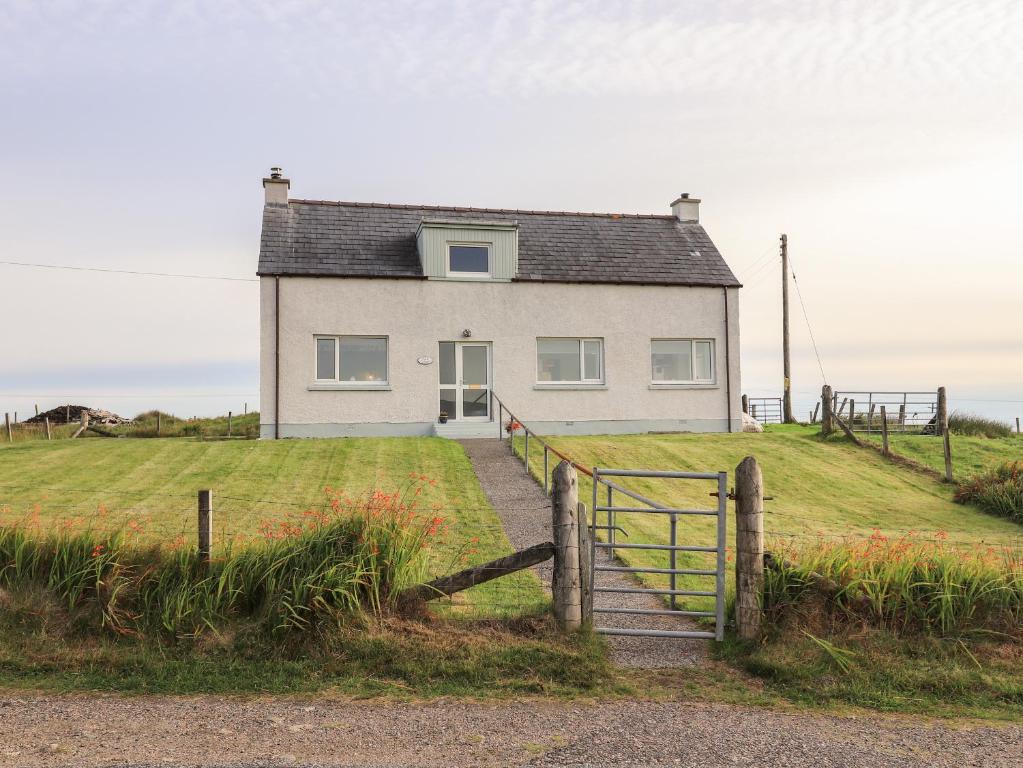 une maison blanche sur une colline avec un portail et des escaliers dans l'établissement Park Cottage, à Carinish