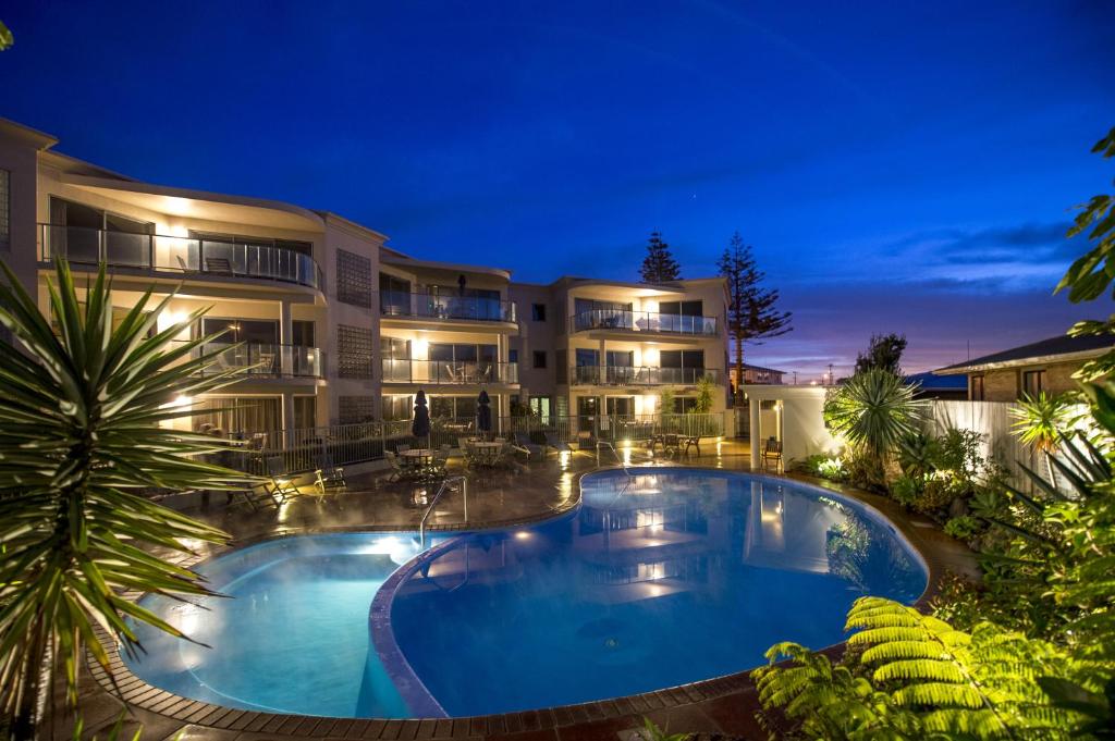 a large building with a large swimming pool at night at The Reef Beachfront Apartments in Mount Maunganui