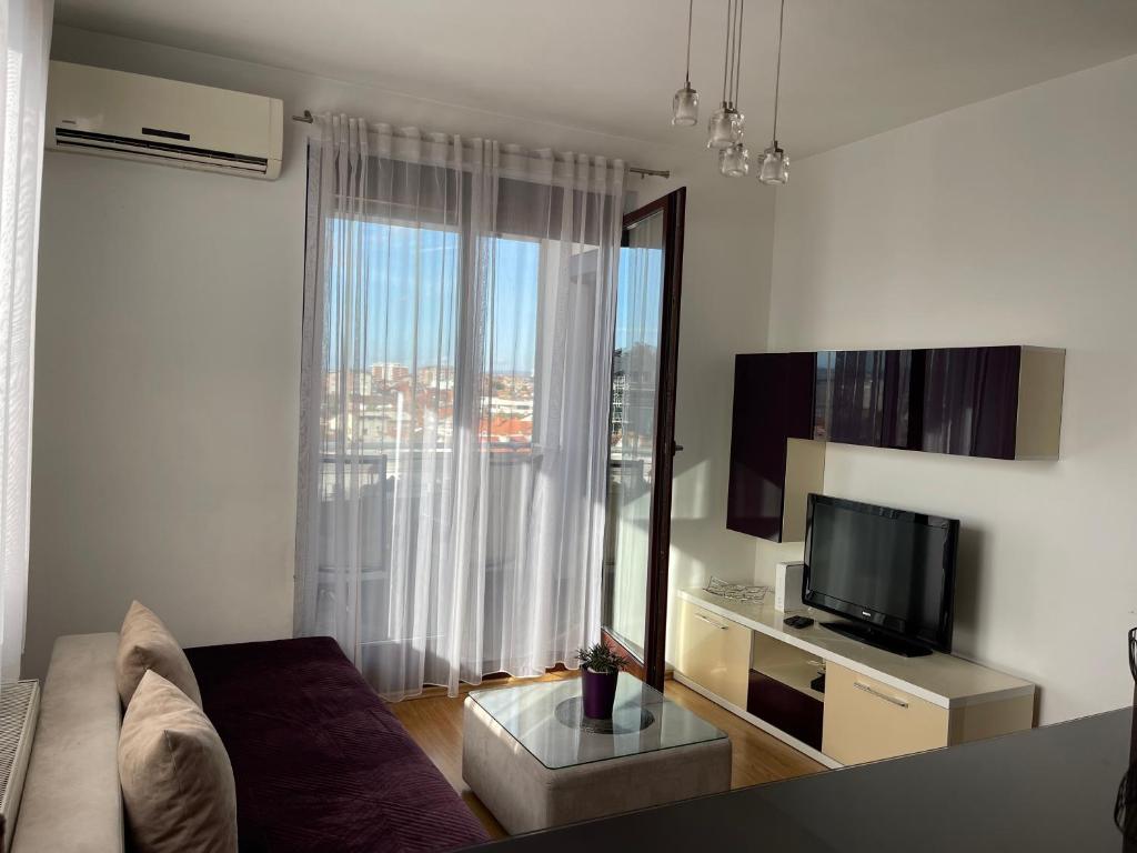 a living room with a couch and a television at Purple apartment- in Prizren