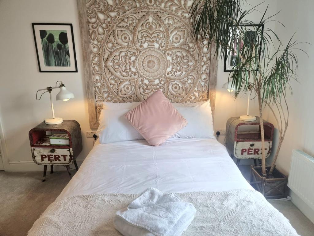 um quarto com uma cama com lençóis brancos e almofadas cor-de-rosa em Stylish 2-bed Flat, Quick Access to London Sights em Londres