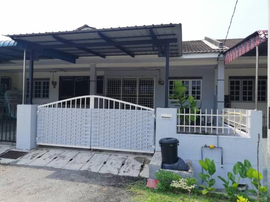 a house with a white gate and a fence at Homestay Eco Rengas Jaya in Padang Rengas