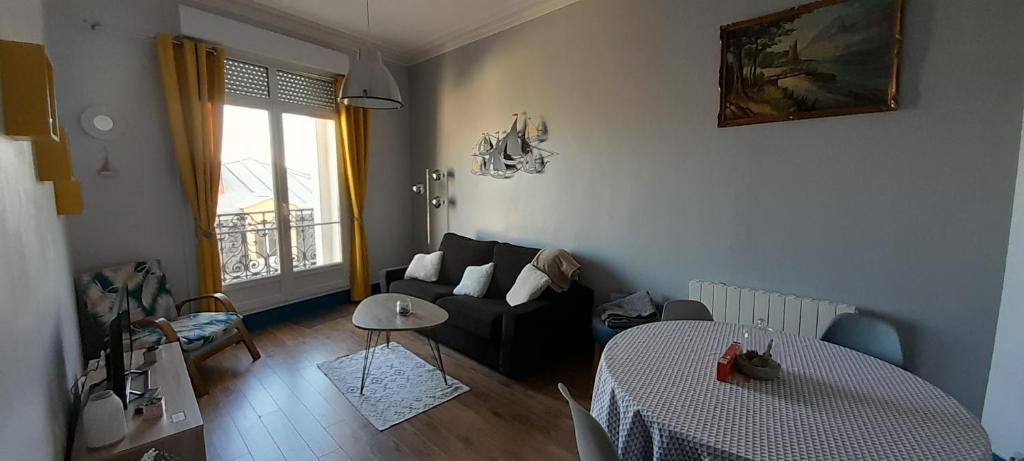 ein Wohnzimmer mit einem Sofa und einem Tisch in der Unterkunft Au bon air in Wimereux