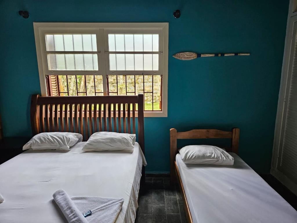 2 camas individuais num quarto com uma janela em Pousada da Mary em Ubatuba