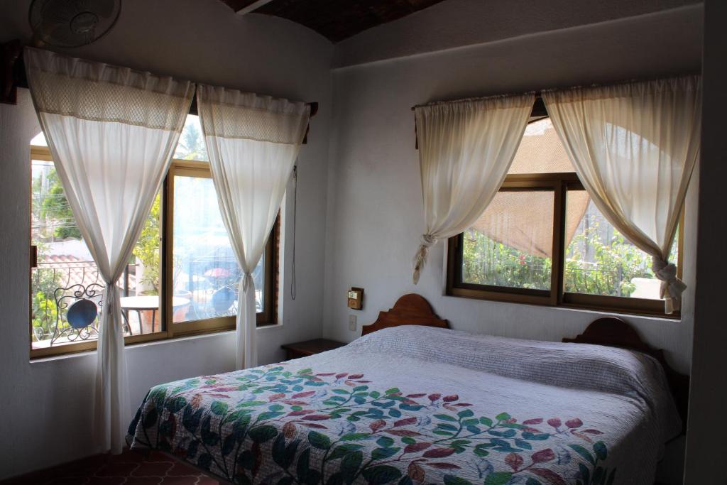 sypialnia z 2 oknami i łóżkiem z kocem w obiekcie Bungalows Las Tortugas w mieście Lo de Marcos