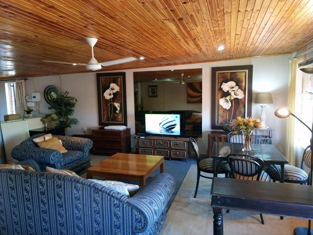 a living room with blue couches and a wooden ceiling at Douglasdale 3 Queen Double Beds Loft - 2nd Bedroom own entrance kitchenette & bathroom- Parking - Serviced - Wood & Gas Braais - Pool & Lapa - Ultra Hi Speed WiFi with DSTV & Movie Streaming - Full office backup - in room iMac & iPad - Printer & Copier in Sandton