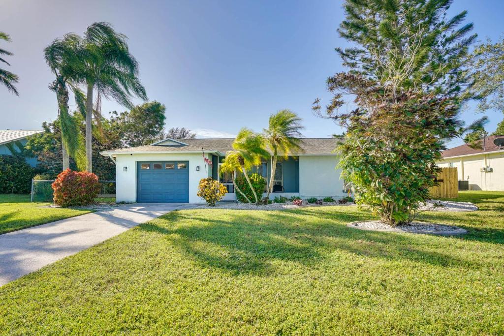 een huis met een blauwe garage en palmbomen bij Bright Home with Outdoor Oasis, 7 Mi to Beaches in Cape Coral