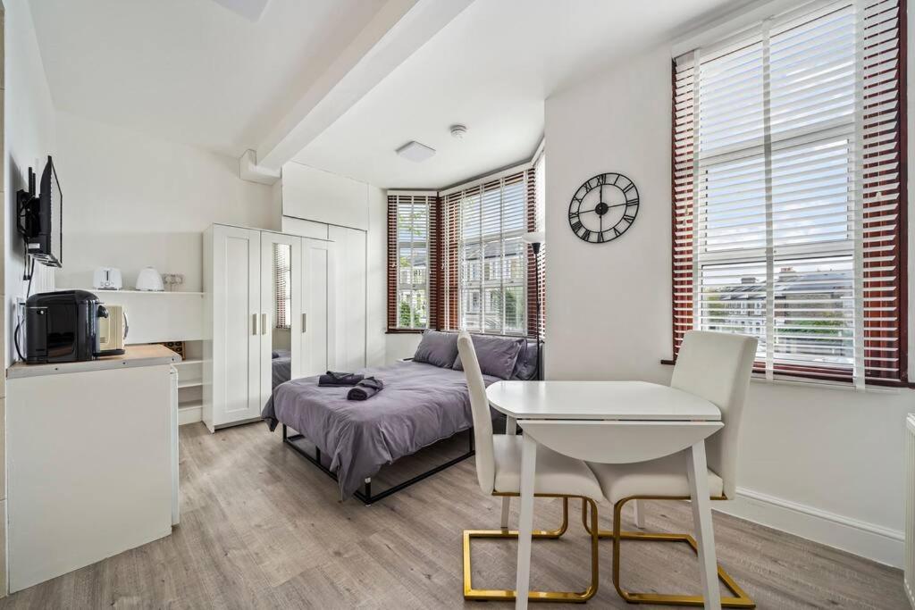 - une chambre avec un lit, une table et une horloge dans l'établissement Charming Flat In Shepherds Bush, à Londres