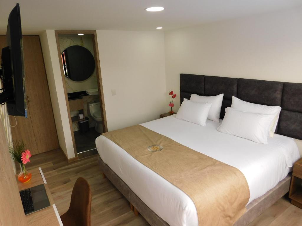 1 dormitorio con 1 cama grande y TV en HOTEL MX BOGOTA, en Bogotá