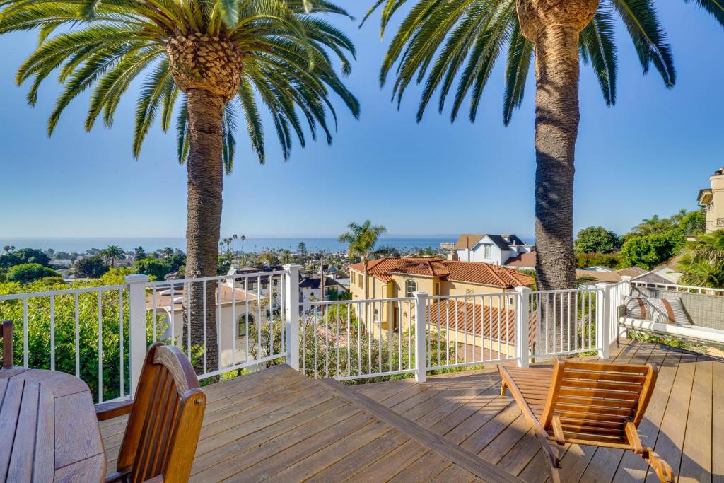 a deck with two palm trees and two chairs at Stunning Ventura Cottage with Deck and Ocean View! in Ventura