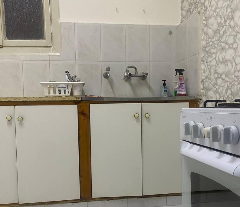 a kitchen with white cabinets and a sink and a stove at Homey Apt. with beautiful view in Amman