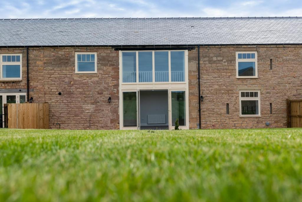 a brick house with a lawn in front of it at La Roche-Barn with hot tub on the Welbeck estate in Holbeck