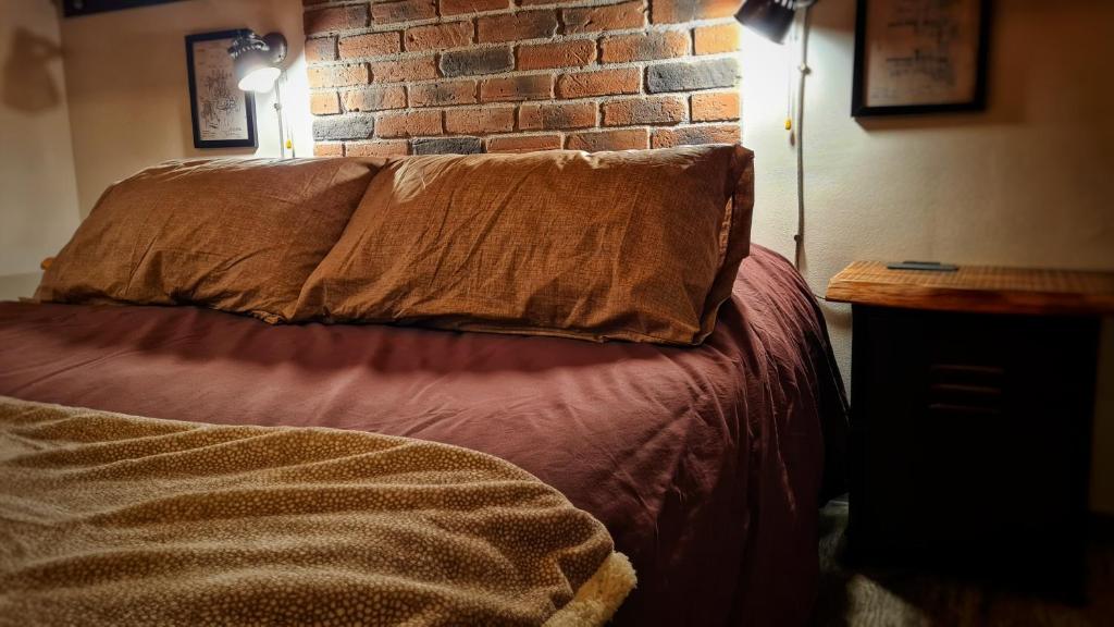 a bed with a pillow and a brick wall at Casa22 in Abbadia San Salvatore