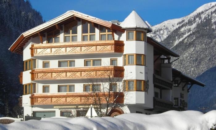 ein großes Gebäude vor einem schneebedeckten Berg in der Unterkunft Hotel Troschana in Flirsch