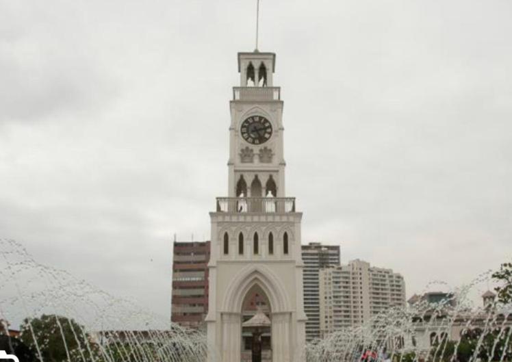 Una torre de reloj alta con un reloj encima. en Cómodo departamento diario céntrico en Iquique