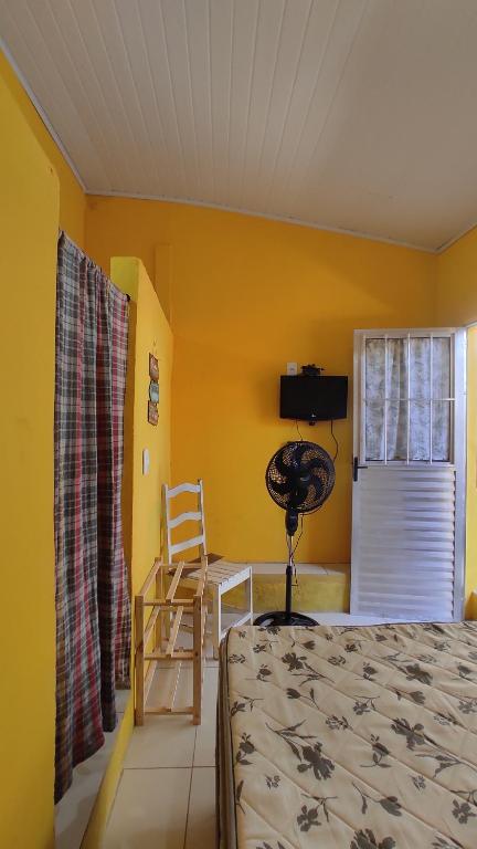 ein Schlafzimmer mit einem Bett, einem Stuhl und einem Fenster in der Unterkunft Quartos simples e aconchegantes na orla de Itaparica in Itaparica Town