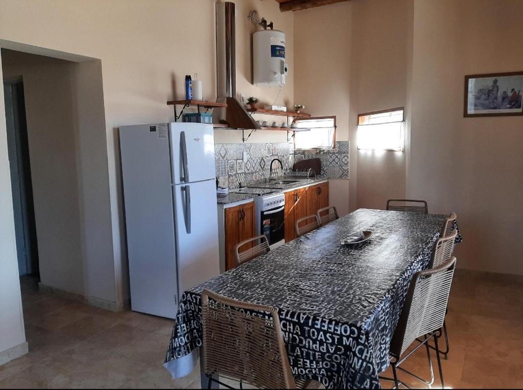 a kitchen with a table and a white refrigerator at Complejo ROSA OLIVA in Albardón