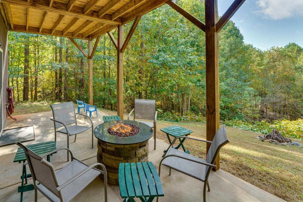 Cozy North Carolina Cabin - Deck, Grill and Fire Pit في Bostic: فناء مع طاولة وكراسي ومدفأة