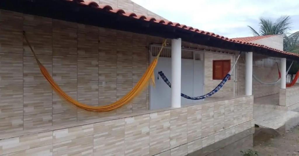 a house with a hammock on the side of it at Chalé Encanto do Mar 1 in Luis Correia