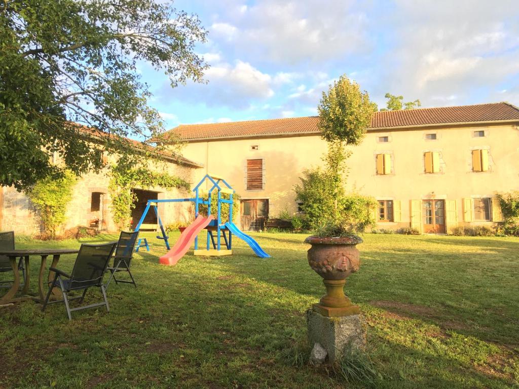 un patio con parque infantil, mesa y edificio en Le Bos Clard, en Félines