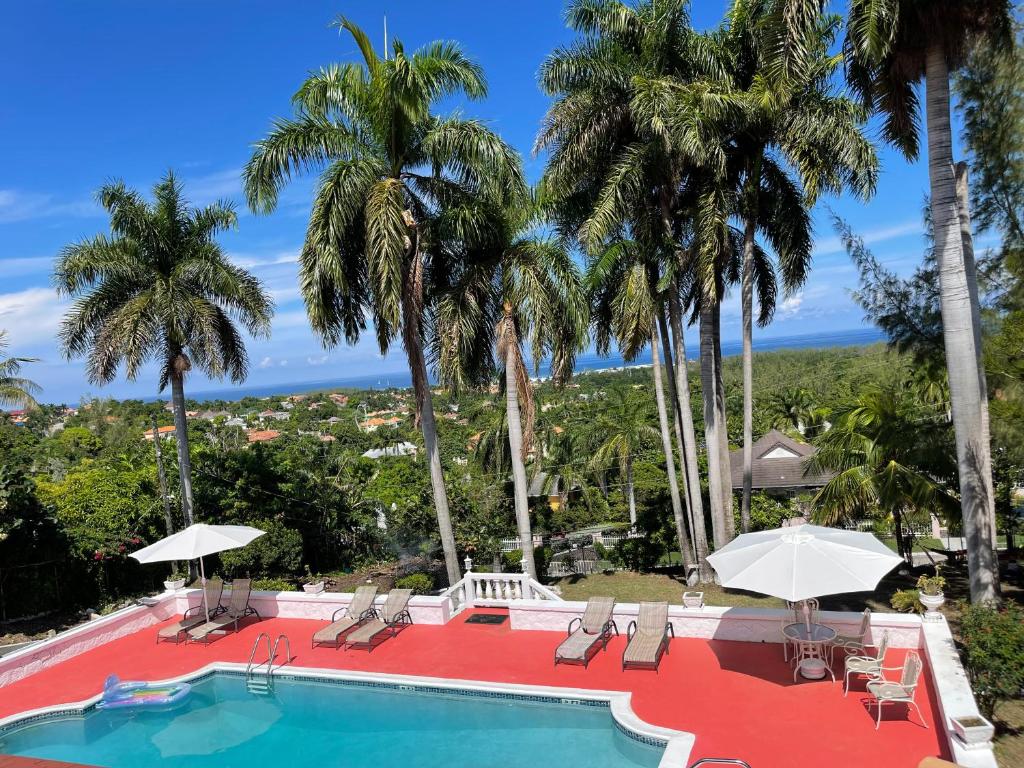 uma piscina de resort com palmeiras e o oceano em Peaceful Palms Montego Bay em Montego Bay