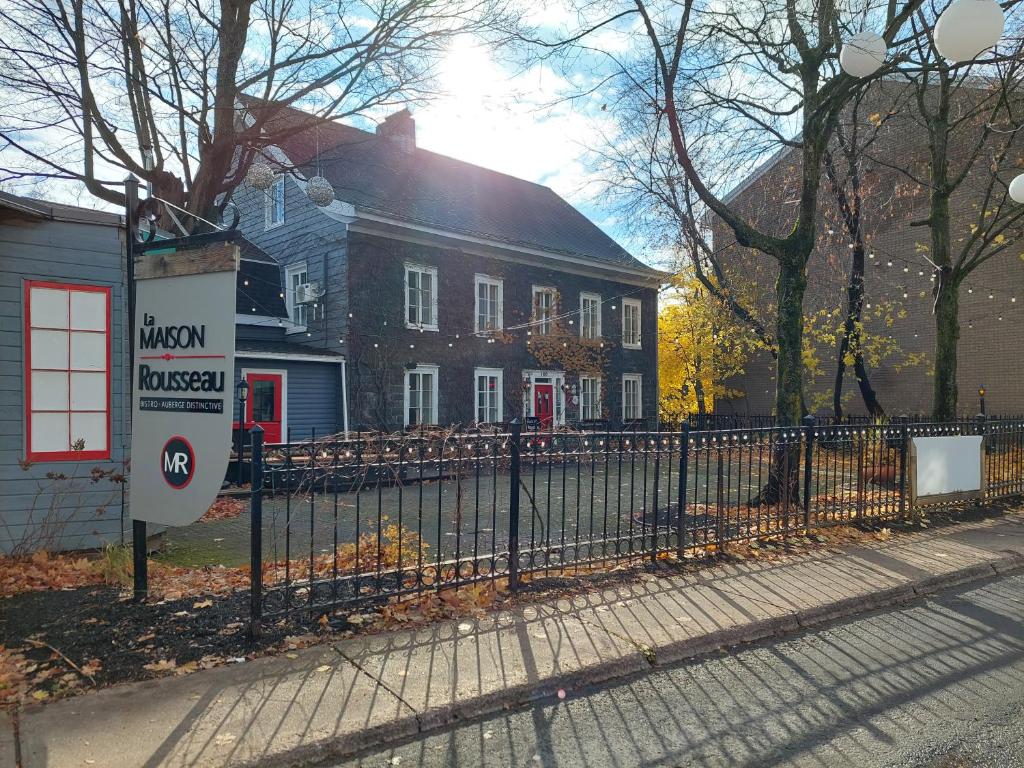 uma cerca de ferro forjado em frente a uma casa em La Maison Rousseau em Montmagny