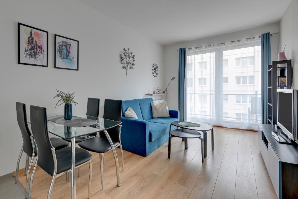 a living room with a blue couch and a table and chairs at Wave Apartments Nowa Grobla Old Town in Gdańsk