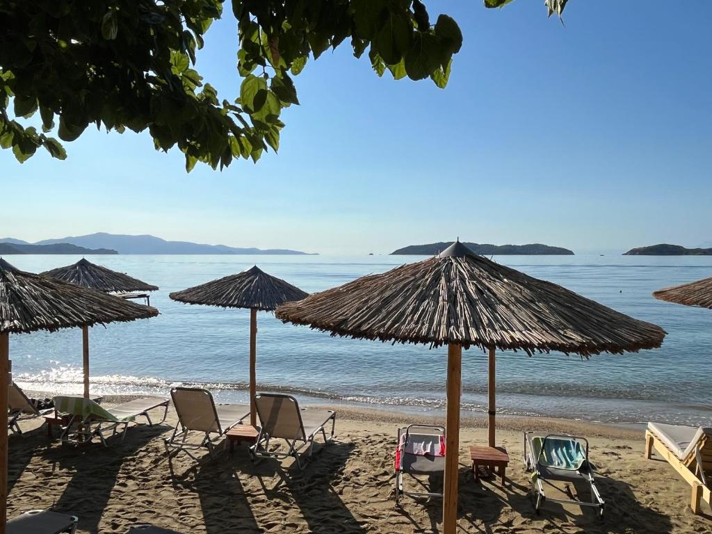 a group of chairs and umbrellas on a beach at Maniatis Garden in Achladies
