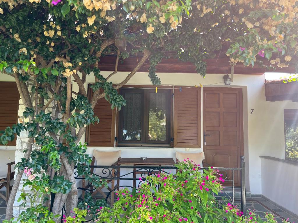 a table and chairs under a tree next to a door at Maniatis Garden in Achladies