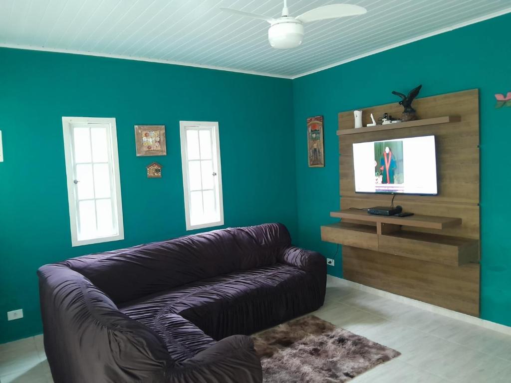 ein Wohnzimmer mit Sofa und Flachbildfernseher in der Unterkunft Casa Ampla e Confortável a 10 minutos Praia Ubatumirim Cambuca in Ubatuba