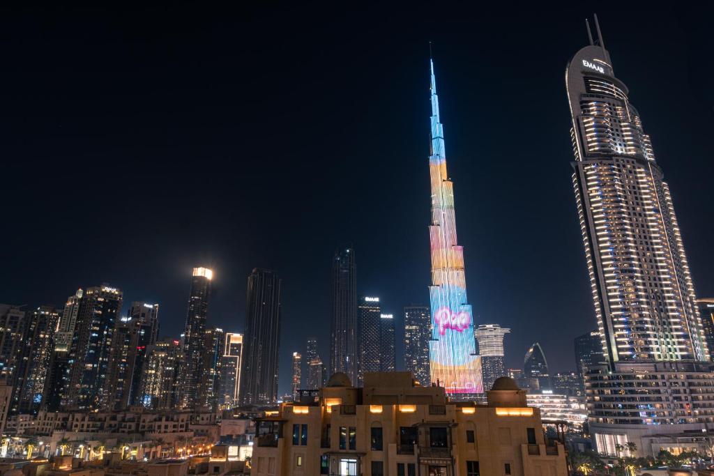 een verlichte stad 's nachts met een hoog gebouw bij FIRST CLASS 2BR with full BURJ KHALIFA view in Dubai