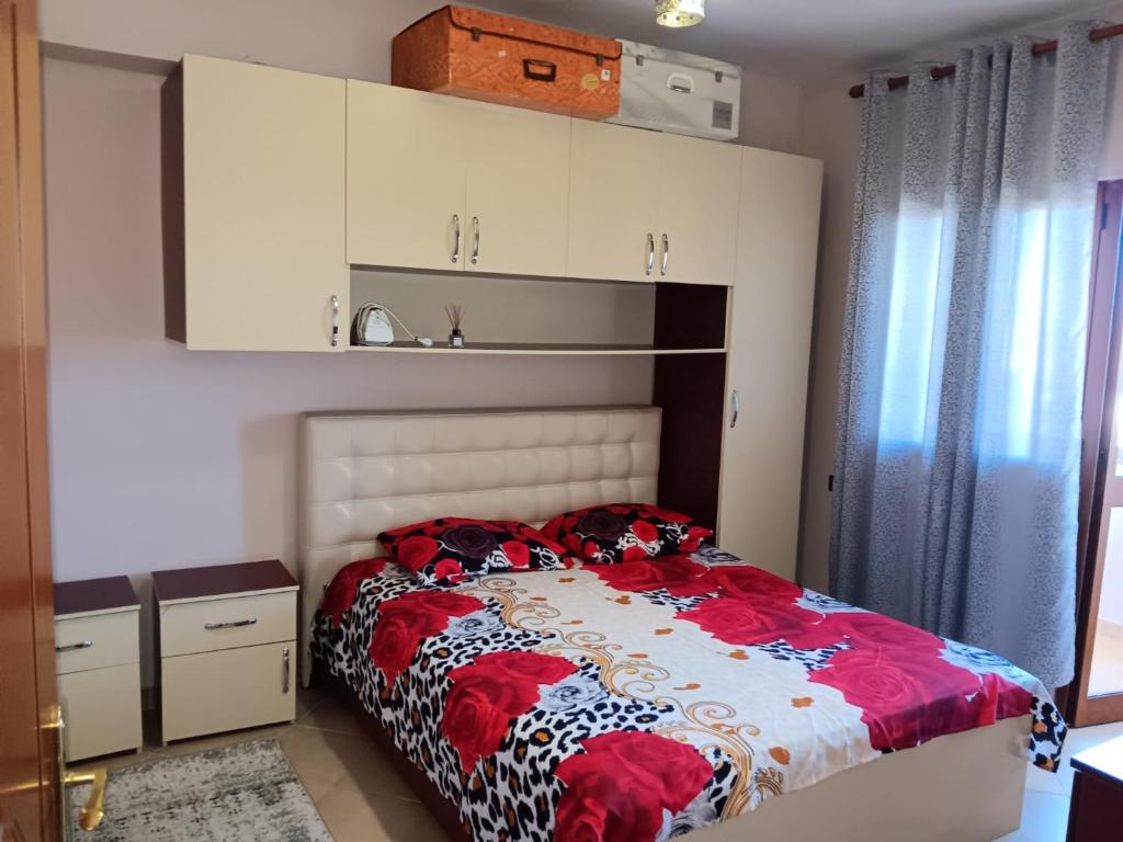 1 dormitorio con 1 cama con edredón rojo y blanco en Alvi apartment en Shkodër