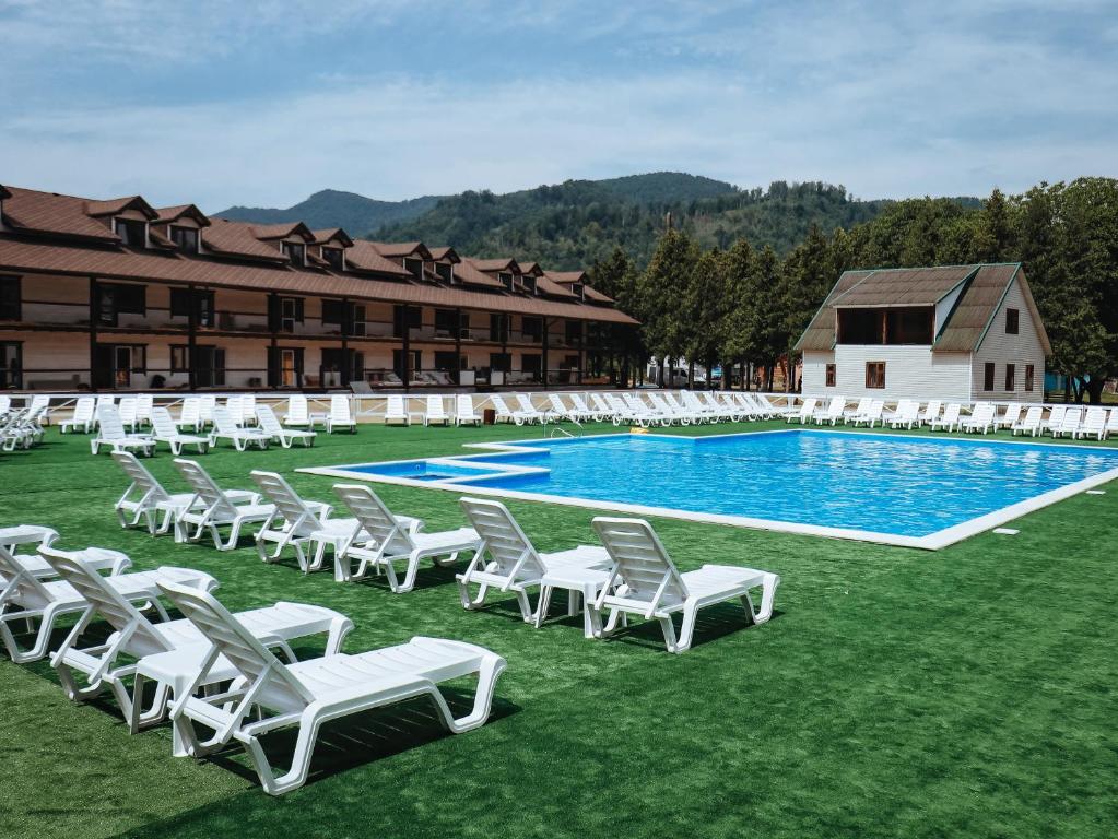 a group of white chairs and a swimming pool at Парк-готель Там, де гори... in Vyzhnytsya