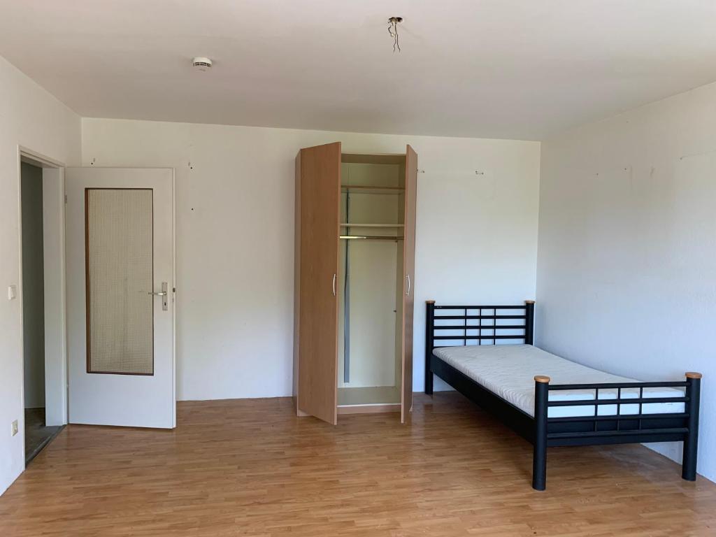 ein leeres Zimmer mit einem Bett und einem Schrank in der Unterkunft Solinger Wohnung in Solingen