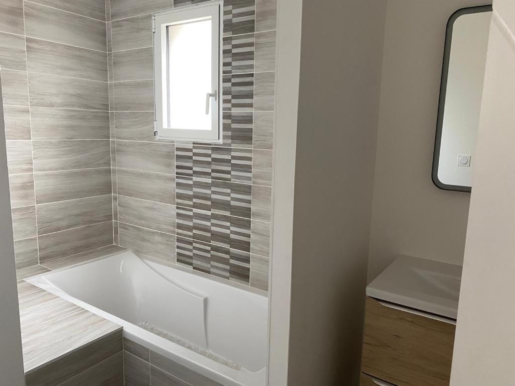 a white bath tub in a bathroom with a window at Maison neuve cosy à 20 min des plages #lorient #cosy in Pont-Scorff