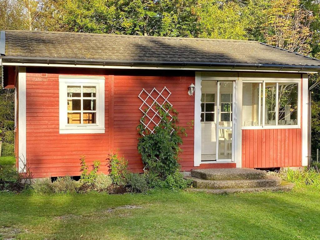 uma pequena casa vermelha com uma porta branca e janelas em Holiday home TORUP em Torup