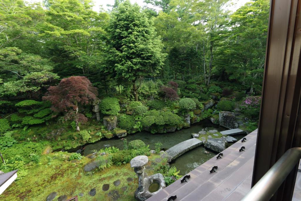 a view of a garden with a river and trees at Teiensaryo Yamanakako in Yamanakako