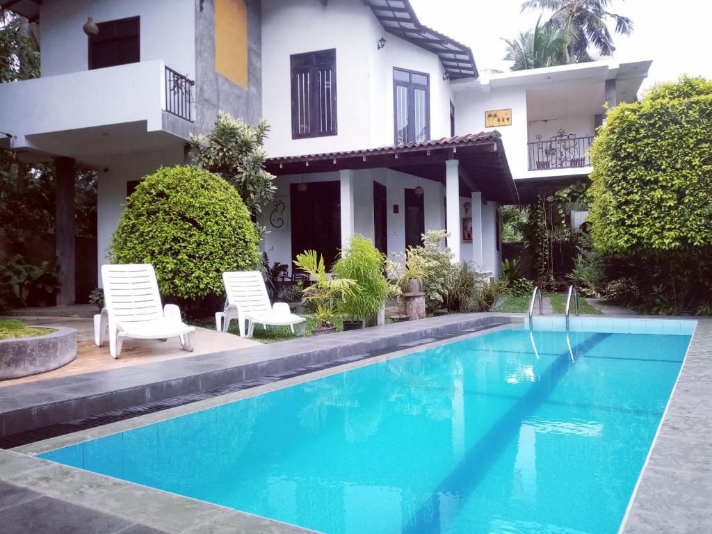 a swimming pool in front of a house at Om Villa in Hikkaduwa