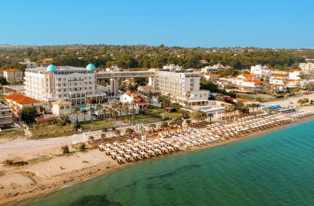 アギア・トリアダにあるサンタ ビーチ ホテルの傘と建物のある海辺の空中風景